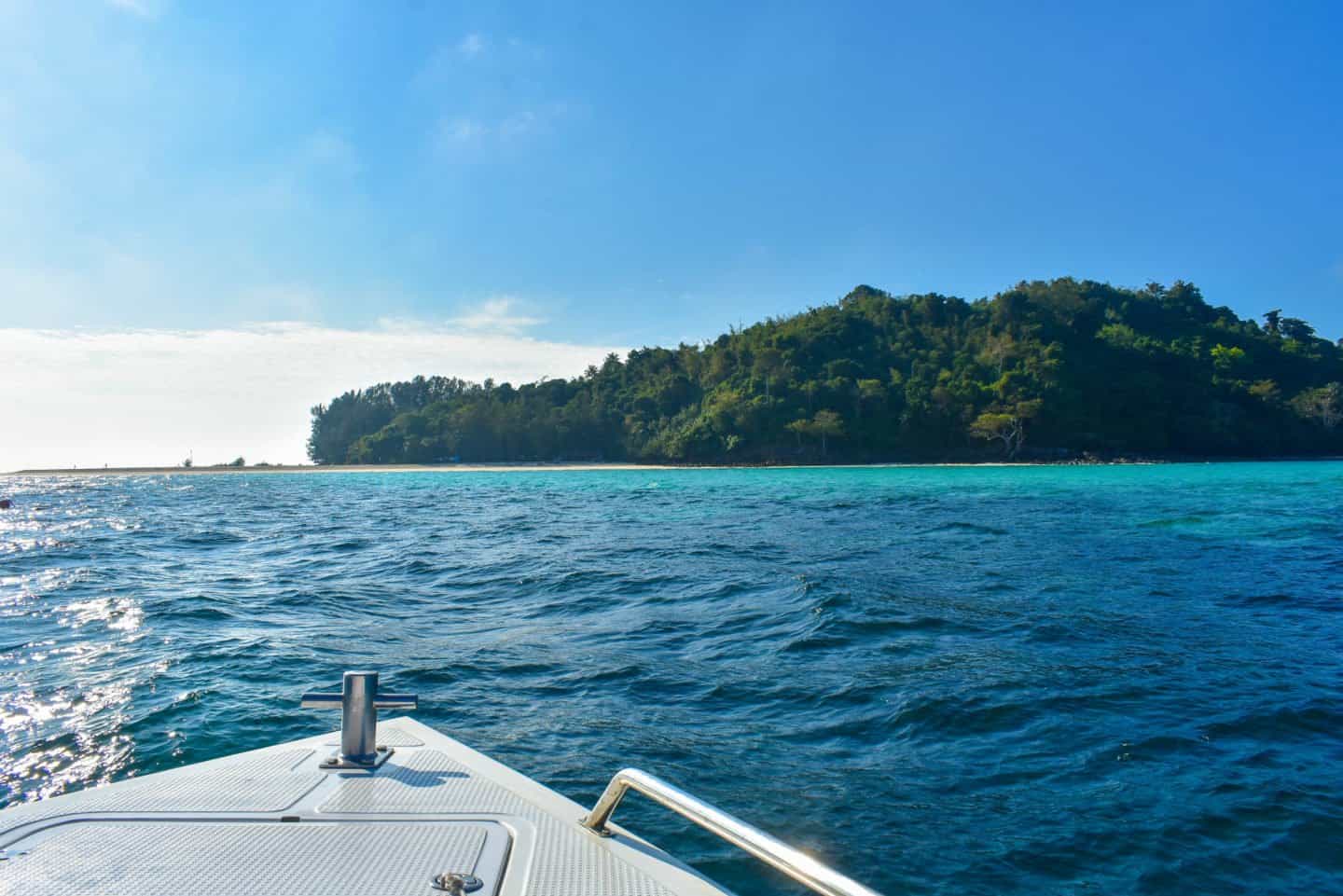 Speedboat heading towards a forested island on a Phi Phi day trip