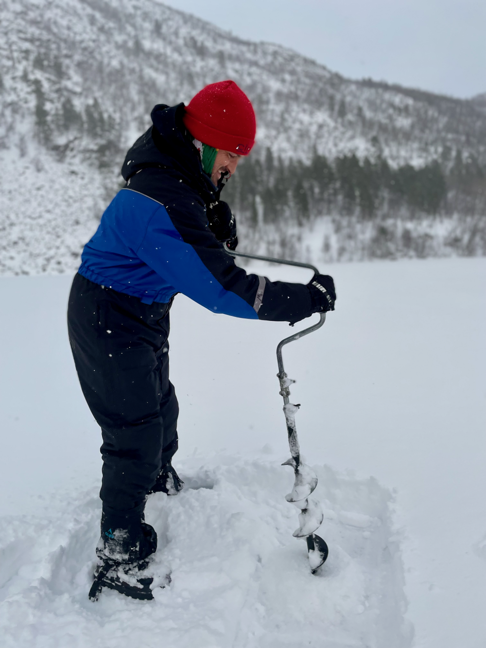 Greg using the tool to drill into the lake for ice fishing